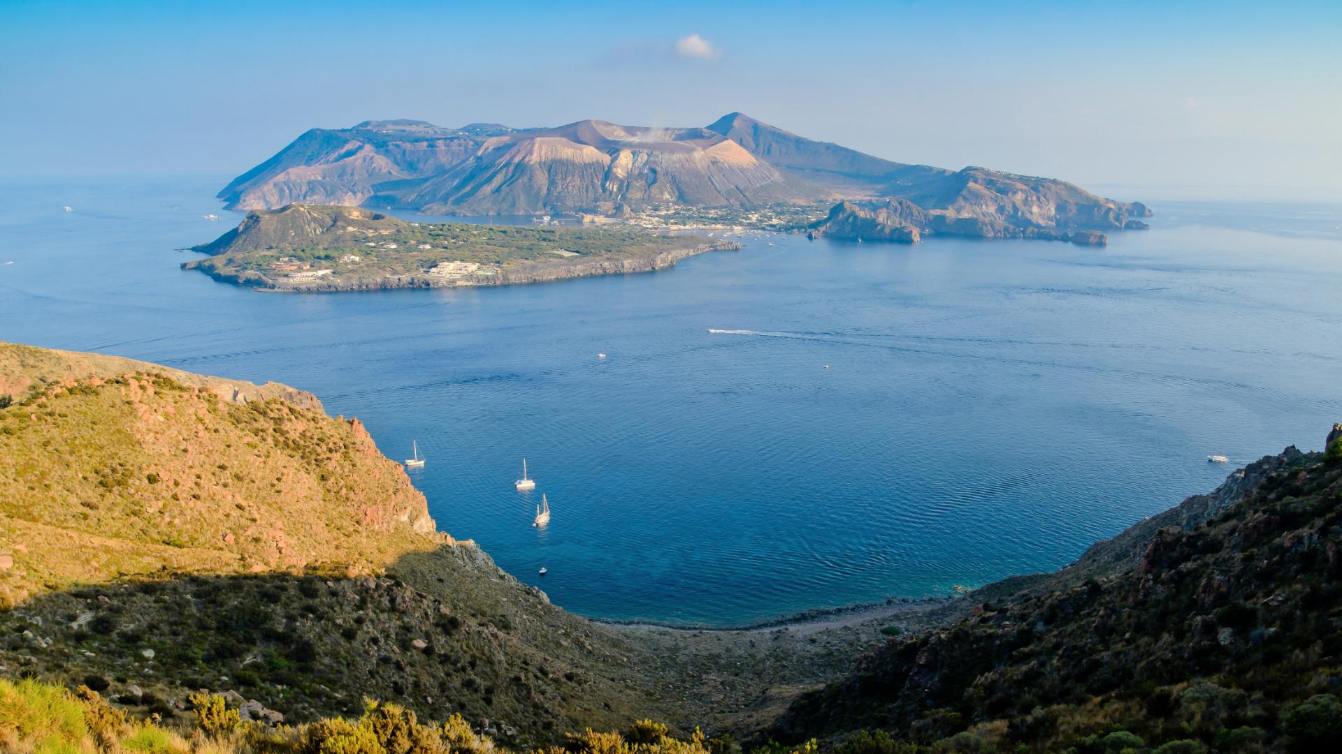 Vista panoramica di un'isola vulcanica con mare e barche.