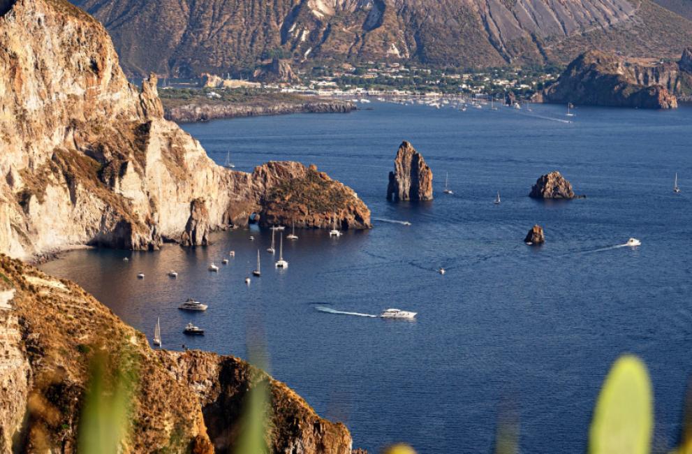 Panorama delle isole Eolie con mare blu e barche a vela.